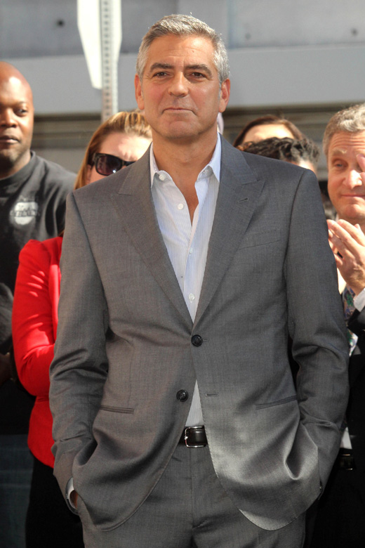 Актер и продюсер Джордж Клуни в сером костюме на красной дорожке
