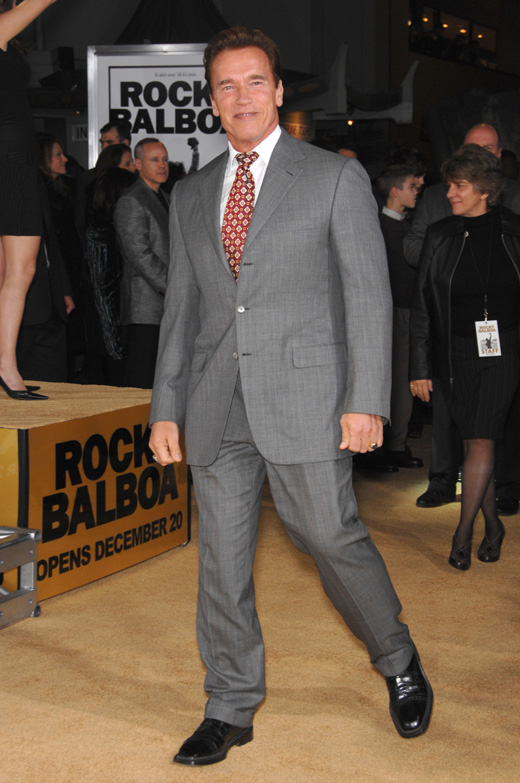 Арнольд Шварценеггер в сером костюме и красном галстуке
